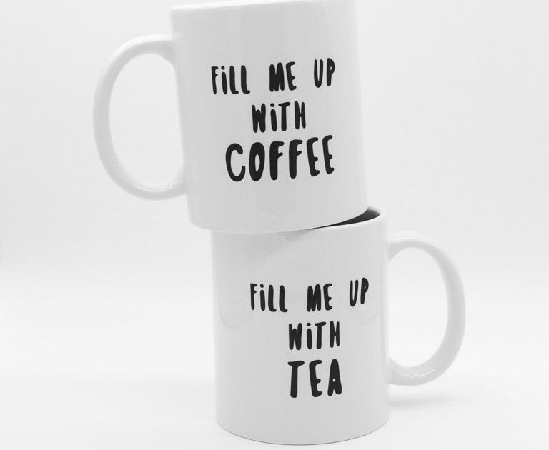 Deux mugs blancs l'un sur l'autre, avec les écritures noires "Fill me up with coffee" et "fill me up with tea".